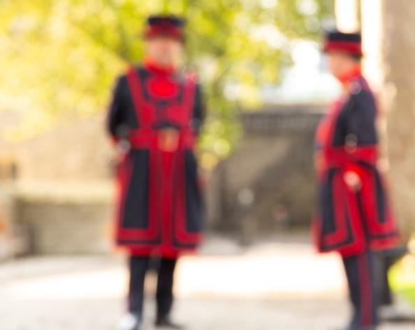 A raven watches 2 beefeaters in the distance